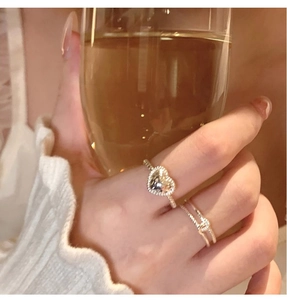 Detail of silver heart ring and twisted rope band worn while holding a wine glass