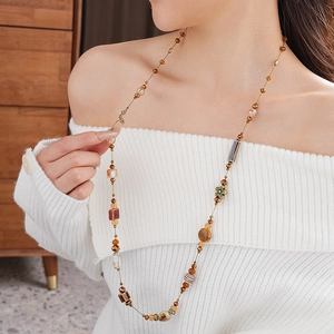 Gros plan du collier en céramique marron avec pendentif fleur sur un pull blanc