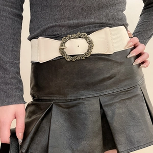 Détail de la ceinture élastique blanc cassé avec boucle en bronze sur vêtements sombres
