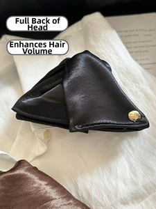 Détail de la pince à cheveux en satin noir avec un bouton doré gravé d'un message