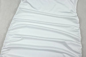 Detail of white glossy elastic fabric with side ruched design on the slim fit dress