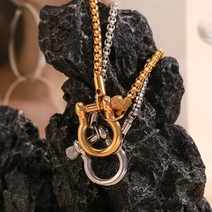 Detail of 18K gold plated stainless steel shackle pendant on a textured black stone
