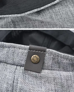 Close-up of grey linen newsboy cap fabric texture with metal button and leather detail