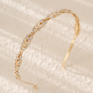 Close-up of golden leaf vine headband with sparkling crystals on beige fabric