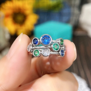 Detailed close-up of a silver ring with embedded blue and green round gemstones