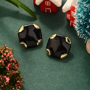 Macro detail of square vintage black and gold earrings on a festive Christmas background