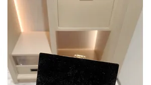 Close-up of elegant black velvet clutch bag with premium gold metallic clasp and hardware