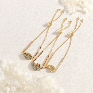 Detailed view of sea shell and conch pendants with colorful cubic zirconia on gold bracelets