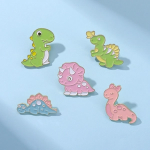 Set of five colorful dinosaur enamel pins with polished gold borders on a light blue surface