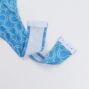 Close-up of blue wave print bodysuit bottom featuring three white resin snap buttons