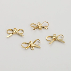 Detailed view of four 14K gold-plated bow-shaped metal pendants for DIY jewelry making