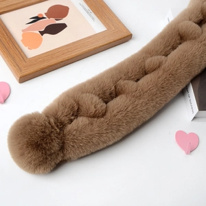 Detail of soft brown faux rabbit fur scarf with plush texture and round pom-pom design