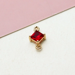 Close-up of gold-plated geometric rhombus pendant with a red zircon gemstone insert