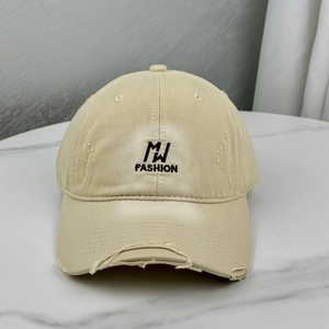 Detailed close-up of distressed brim and black embroidery on khaki cotton baseball cap