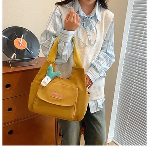 Detail of yellow canvas tote bag with FASHION label and green plush charm accessory
