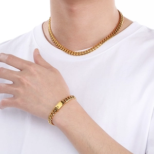 Male model wearing 8mm gold stainless steel Cuban chain necklace and bracelet set