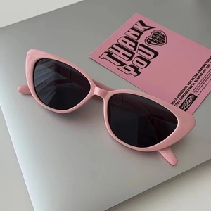Pink cat eye sunglasses with dark lenses placed on a laptop surface for a trendy aesthetic
