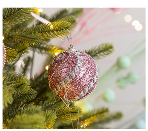 Close-up of pink foam Christmas ball with sequins and wave patterns on a green tree