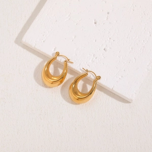 Macro shot of chunky gold teardrop hoop earrings with high-polish mirror finish on stone