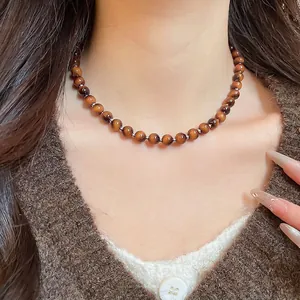 Tiger eye beaded necklace with silver accents worn by a model on a brown sweater
