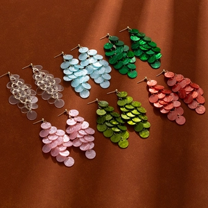 Macro shot of colorful shell tassel earrings in multiple shades on a textured background