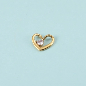 Détail d'un pendentif cœur doré avec pierre de naissance rose sur fond bleu clair