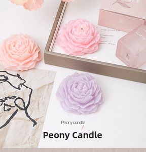 Detailed view of pink peony scented candles with matching gift boxes on a display tray