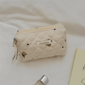 Close-up of beige corduroy pouch featuring cute bear embroidery and quilted pattern