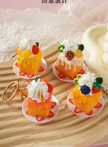 Details von vier Miniatur-Kuchen mit Sahne, Obst und goldenen Schlüsselanhängern