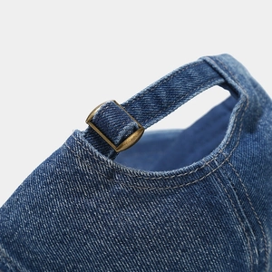 Detail of vintage copper metal buckle and texture on dark blue denim baseball cap