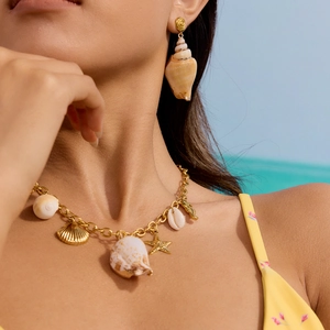 Détail du collier en acier titane doré avec pendentifs coquillages et étoile de mer