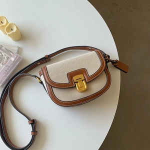 Dettaglio borsa a sella in pelle marrone e tela beige con fibbia in metallo dorato