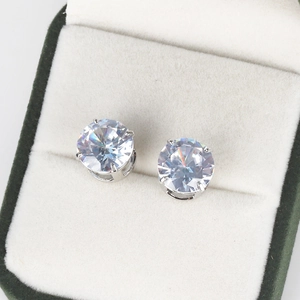 Close-up of classic four-claw round zircon studs in a luxury green jewelry gift box