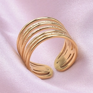 Détail d'une bague multicouche dorée avec texture martelée sur un tissu en soie