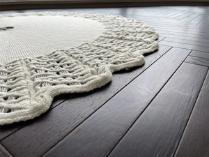 Close-up of knit Christmas tree skirt with hollow wave edges on wooden floor