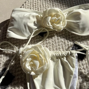 Detail of 3D rose flower accents on cream white bandeau bikini top and side-tie bottoms