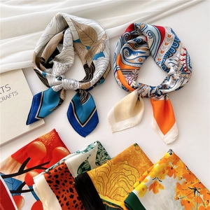 Elegant square silk scarf with paisley and floral prints, tied for a stylish look
