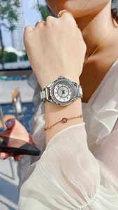 Detail of a ladies' watch with a sparkling rhinestone bezel and white ceramic inlay band