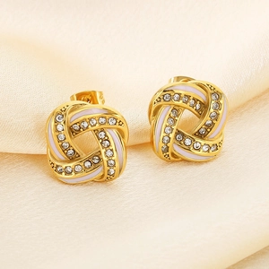 Detail of gold knot earrings with white enamel and sparkling pave cubic zirconia