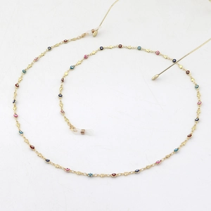 Golden eyewear chain with evil eye beads and stars on white background