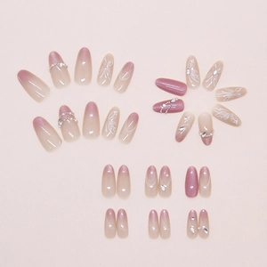 Detail of pink gradient press-on nails with 3D butterfly, pearls, and glitter accents