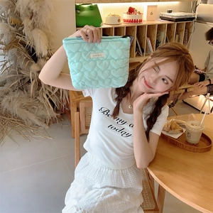 Detailed macro view of mint green quilted heart pattern fabric on a stylish makeup bag