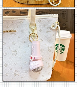 Close-up of a cute pink microphone keychain recorder hanging on a white tote bag