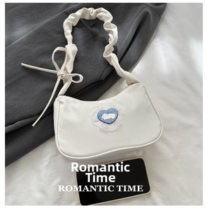 Detail of white underarm bag featuring blue heart patch with rabbit and ruffled strap