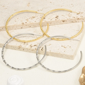 Detailed close-up of gold and silver chunky hoop earrings with wavy hammered texture