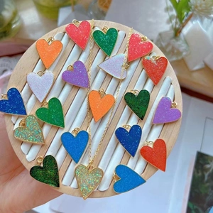 Close-up of assorted heart-shaped pendants with colorful glitter on a wooden display tray