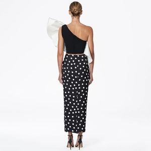 Rear view of black one-shoulder top with white ruffles and polka dot wrap skirt