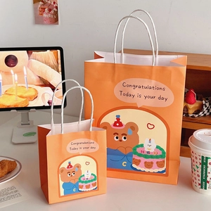 Detailed view of two orange gift bags with cute cartoon bear and birthday cake illustrations