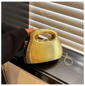 Close-up of golden evening bag with ripple texture and elegant metal chain strap
