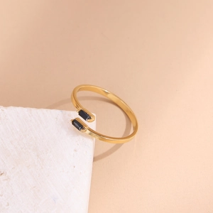 Elegant gold open ring with asymmetrical black rectangular stones on stone pedestal